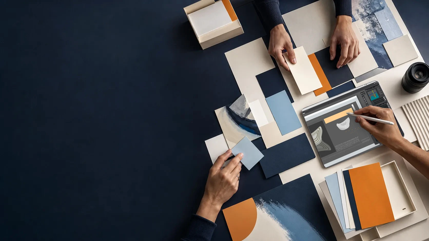 Mesa de trabajo creativo con papeles, muestras de color y herramientas digitales